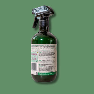 A dark green glass spray bottle with a black trigger sprayer and a white label, shown against a solid green background.